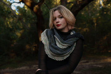 A shot of a hand crocheted  cowl, colored black, light blue, white, and mossy green.