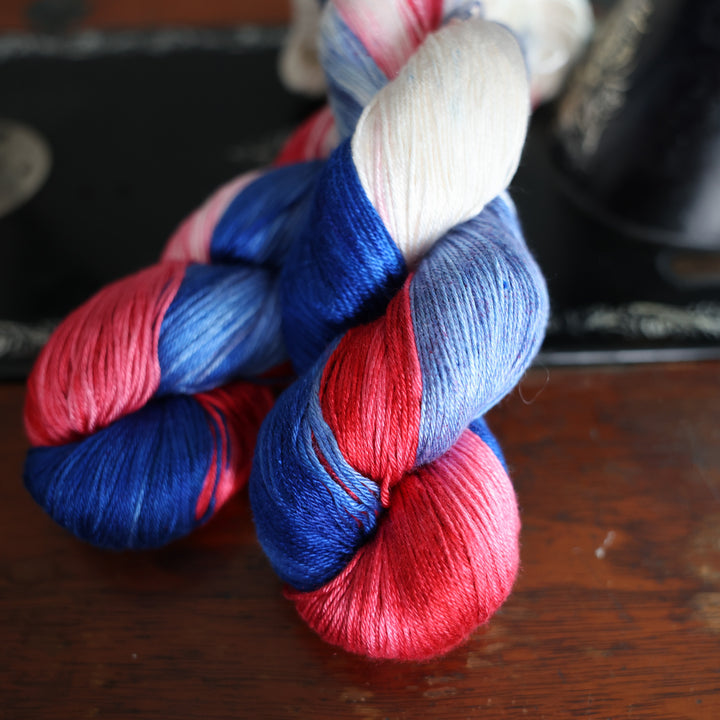 SIlk red white and blue yarn skeins on top of an old fashioned sewing table.