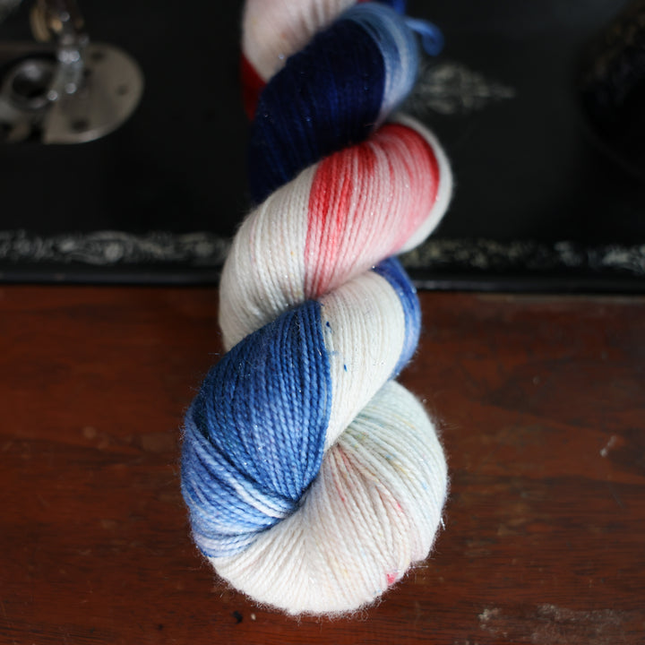 Sparkle red white and blue yarn skeins on top of an old fashioned sewing table.
