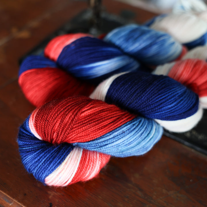 Sport red white and blue yarn skeins on top of an old fashioned sewing table.