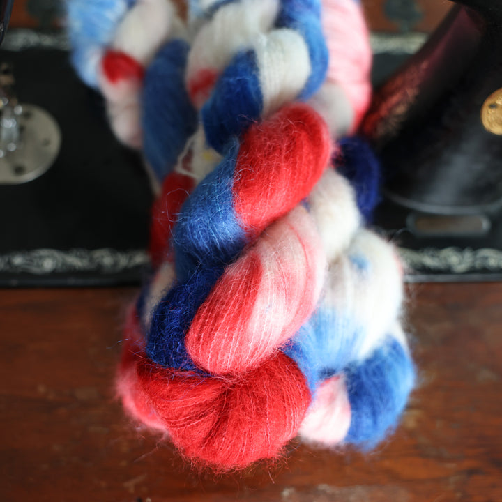 Suri red white and blue yarn skeins on top of an old fashioned sewing table.