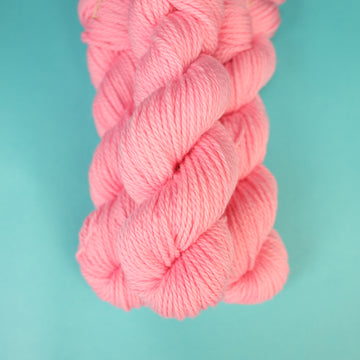 A light pink colored Bulky yarn on top of a light blue background.