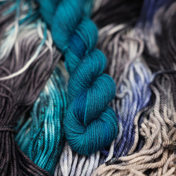 a dark ocean navy blue f-mini yarn on top of unwound black white and blue yarn.
