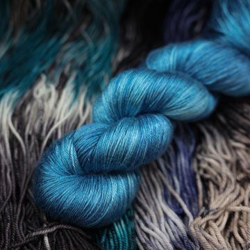 a dark ocean navy blue sport silk on top of unwound black white and blue yarn.