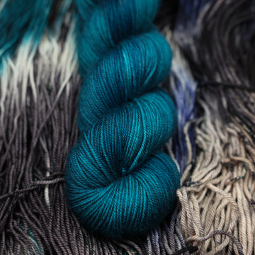 a dark ocean navy blue sport yarn on top of unwound black white and blue yarn.