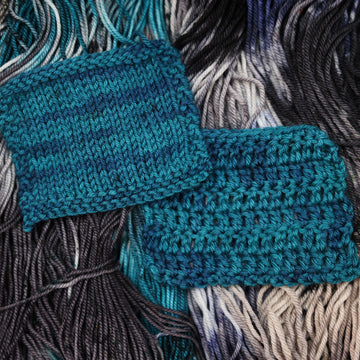 a dark ocean navy blue crochet and knit swatches on top of unwound black white and blue yarn.