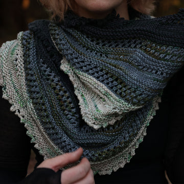 A shot of a person wearing a hand crocheted  cowl, colored black, light blue, white, and mossy green.