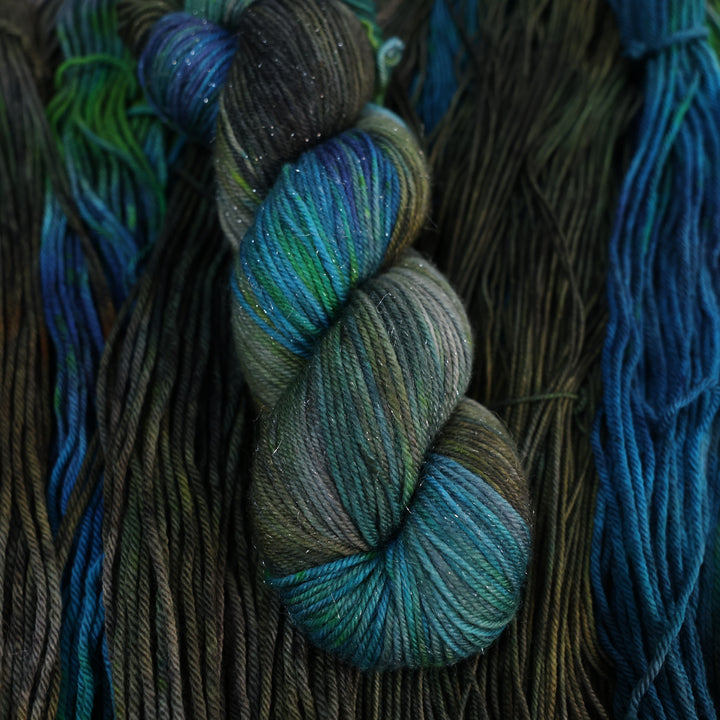 Sparkle DK yarn colored with dark brown dark blue and green. This is all on top of unwound skeins of this same color way.