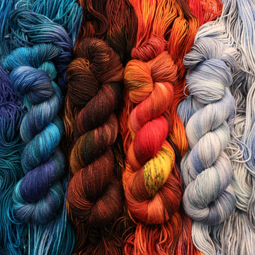 Blue, brown, red, and a light blue/white Sparkle yarn skeins with unwound skeins of each of those colors underneath its corresponding skein.