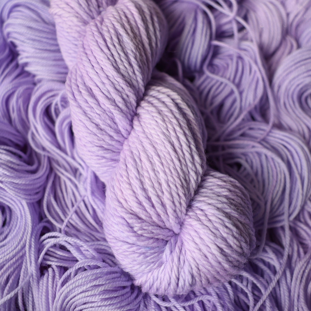 Bulky yarn colored a light violet color on top of unwound skeins of this same color way.