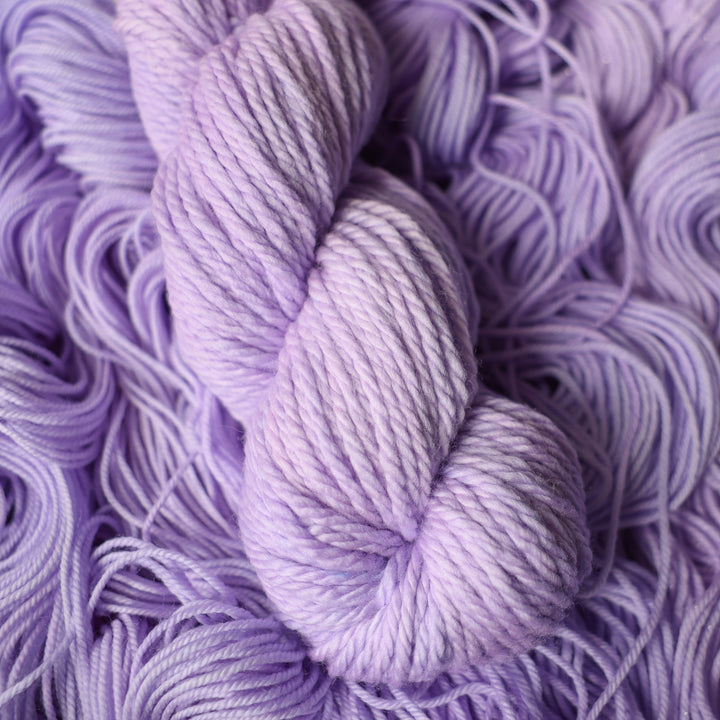 Bulky yarn colored a light violet color on top of unwound skeins of this same color way.