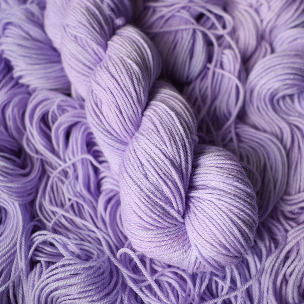 DK yarn colored a light violet color on top of unwound skeins of this same color way.