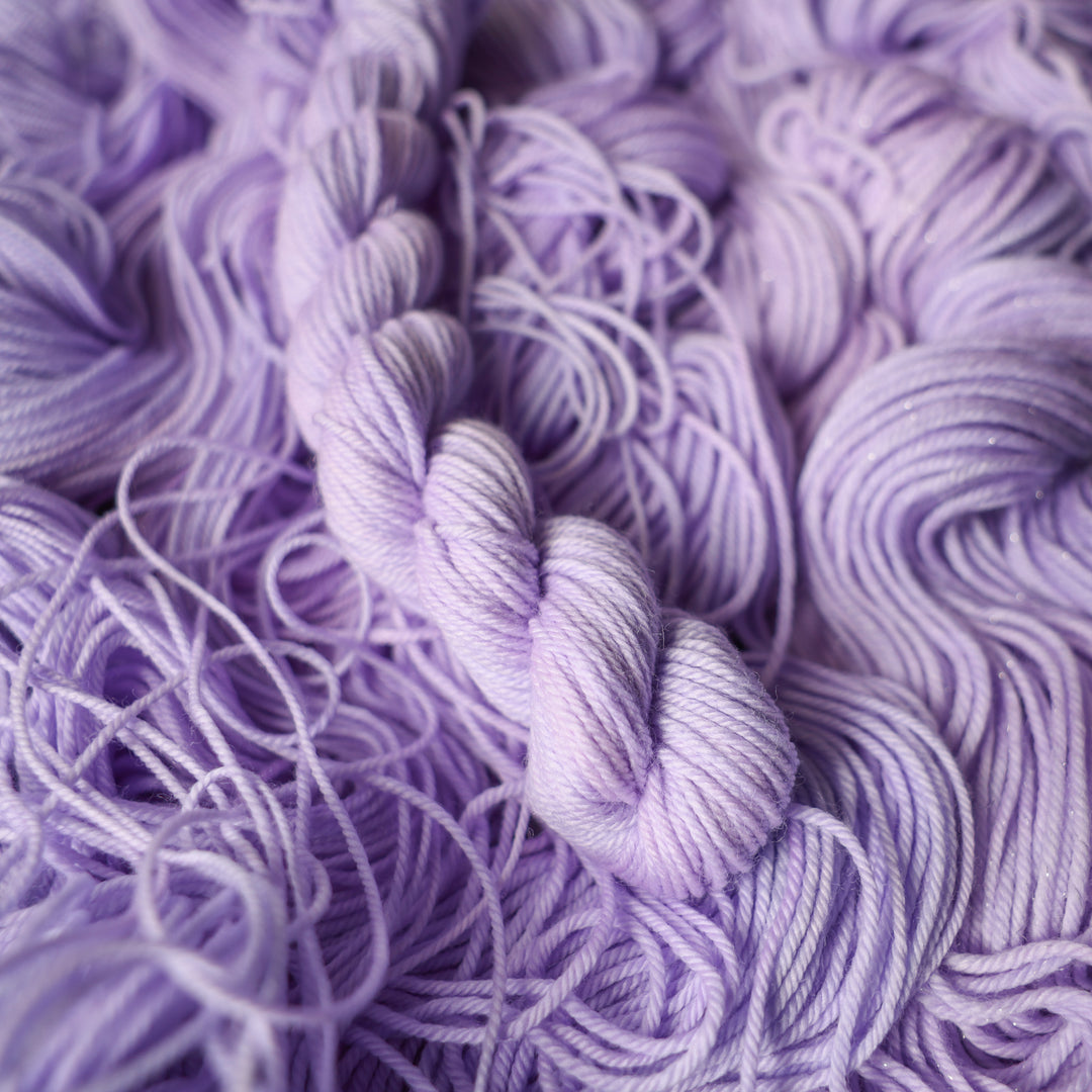 DK mini yarn colored a light violet color on top of unwound skeins of this same color way.