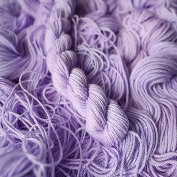 DK mini yarn colored a light violet color on top of unwound skeins of this same color way.