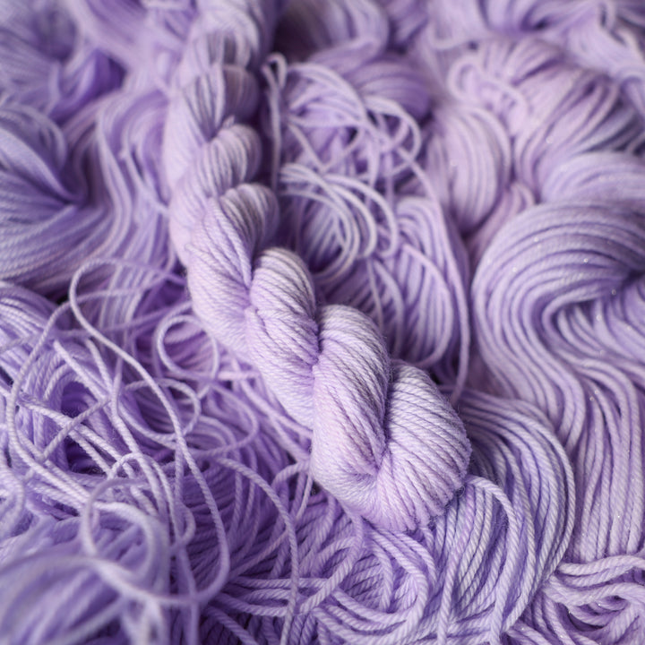 DK mini yarn colored a light violet color on top of unwound skeins of this same color way.