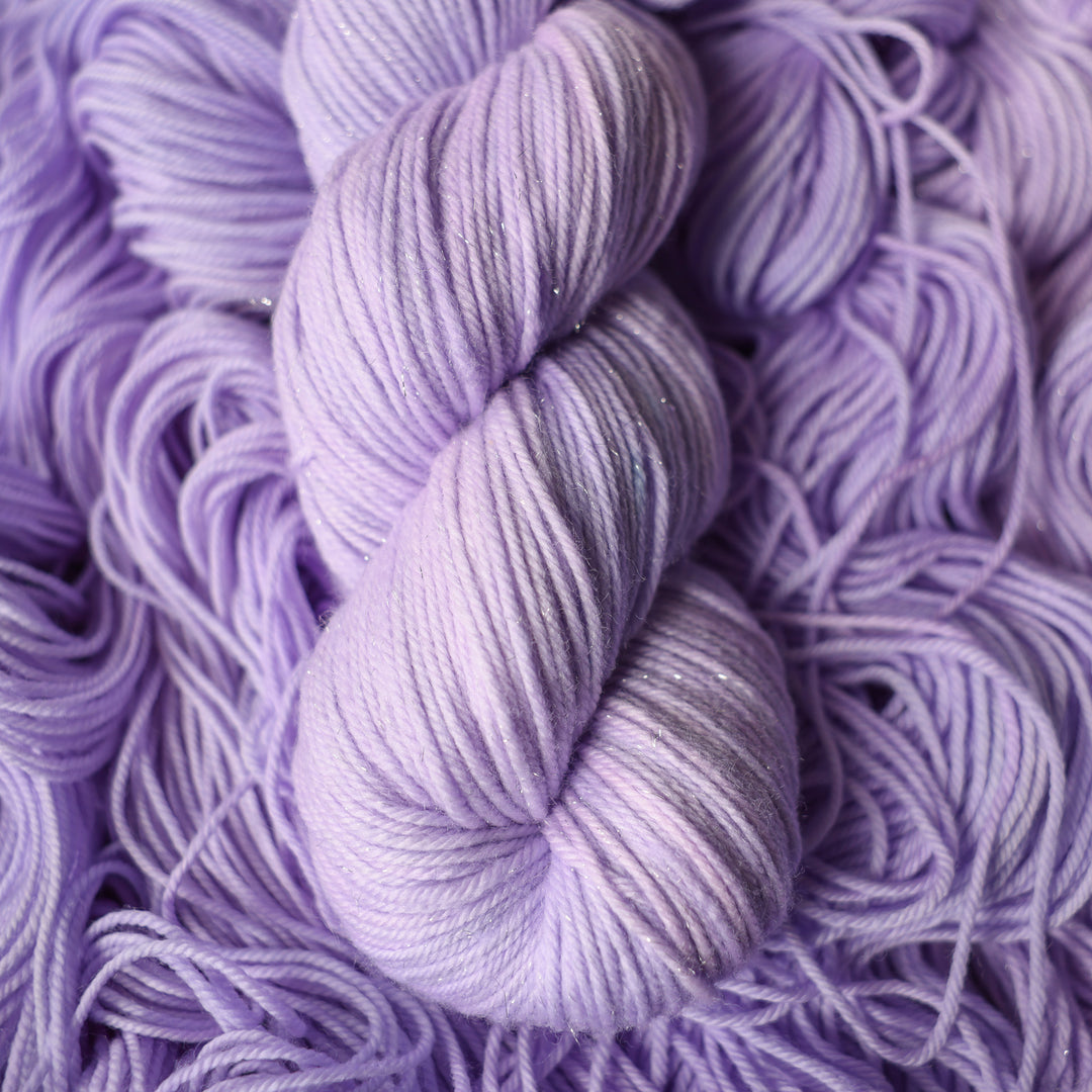 Sparkle Dk yarn colored a light violet color on top of unwound skeins of this same color way.
