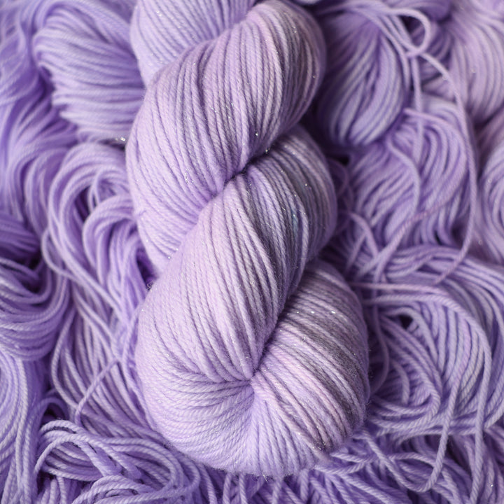 Sparkle Dk yarn colored a light violet color on top of unwound skeins of this same color way.