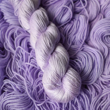Silk yarn colored a light violet color on top of unwound skeins of this same color way.