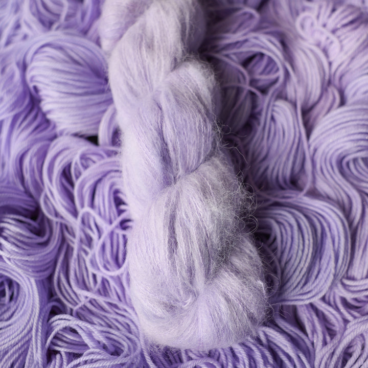 Suri yarn colored a light violet color on top of unwound skeins of this same color way.