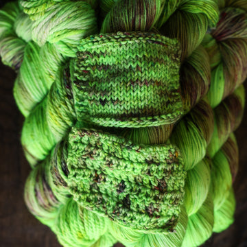 Frankenskein knit and crochet swatch on a wooden table sitting on yarn its made of.