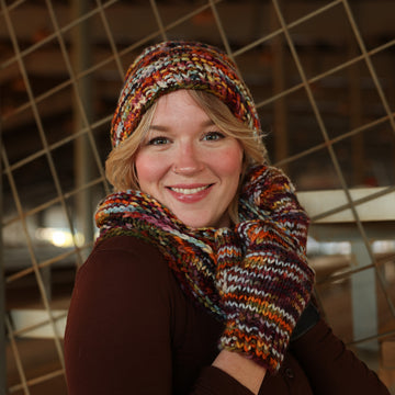 A women wearing hand knit hat, mittens and cowl.