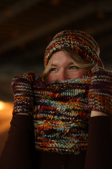 A women wearing hand knit hat, mittens and cowl.