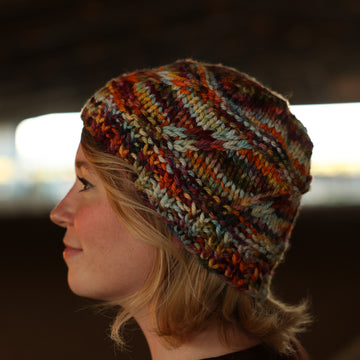 A women wearing hand knit hat that is fall colored.