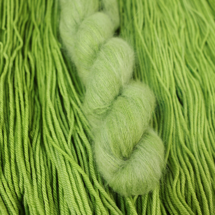 Suri yarn colored a light bright green that is on top of an unwound skein of the same color.