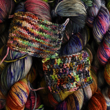 Multi colored knit and crochet swatches on top of already wound multi colored yarn underneath.