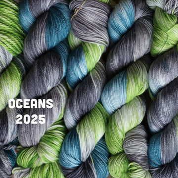 Wound yarn skeins stacked next to each other that are Light lime green, Blue, and grey, colored with some white mixed in.