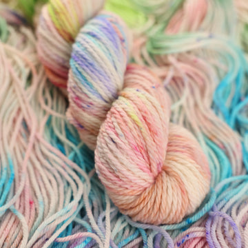 Multi colored light pastel colored Bulky yarn with more unwound multi colored light pastel colored yarn underneath.