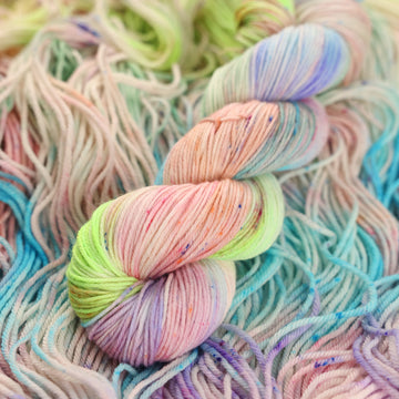 Multi colored light pastel colored DK yarn with more unwound multi colored light pastel colored yarn underneath.