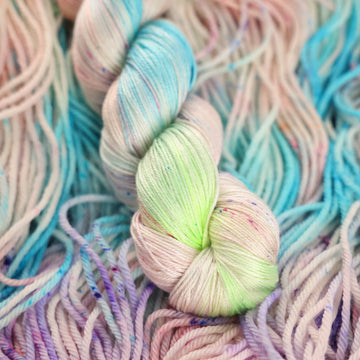 Multi colored light pastel colored silk yarn with more unwound multi colored light pastel colored yarn underneath.