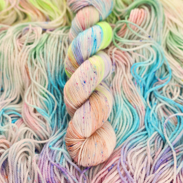 Multi colored light pastel colored sport yarn with more unwound multi colored light pastel colored yarn underneath.