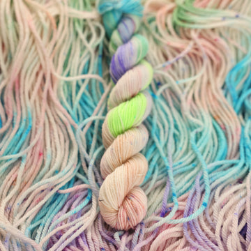 Multi colored light pastel colored mini yarn with more unwound multi colored light pastel colored yarn underneath.