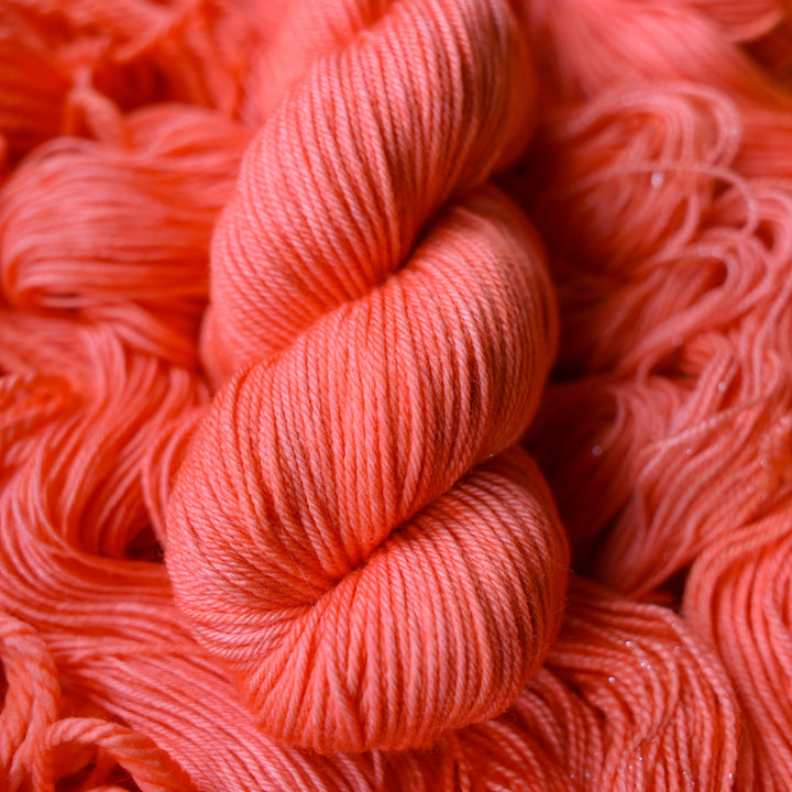 DK yarn colored a light pink color, this skein is on top of unwound skeins of this same color way.