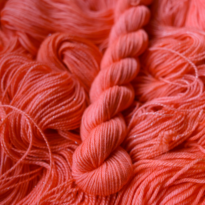 Fingering mini yarn colored a light pink color, this skein is on top of unwound skeins of this same color way.