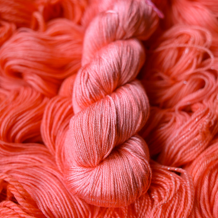 Silk yarn colored a light pink color, this skein is on top of unwound skeins of this same color way.