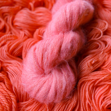 Suri yarn colored a light pink color, this skein is on top of unwound skeins of this same color way.
