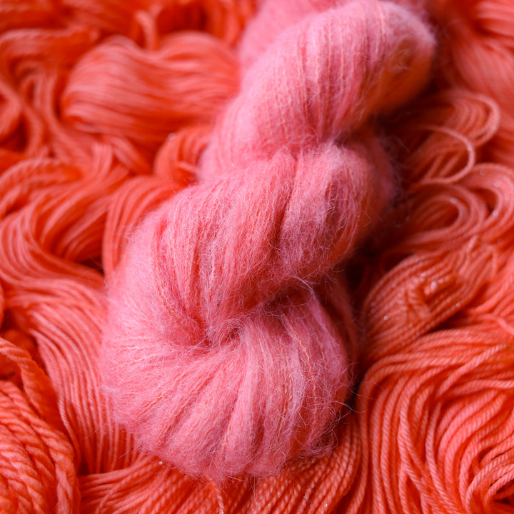 Suri yarn colored a light pink color, this skein is on top of unwound skeins of this same color way.
