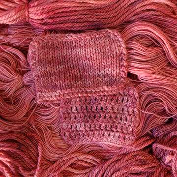 light pink knit and crochet swatches with more unwound light pink yarn underneath.