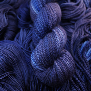 A dark sapphire colored bulky yarn on top of that same yarn, but its unwound.