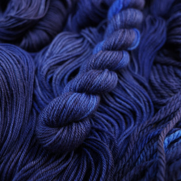 A dark sapphire colored DK-mini yarn on top of that same yarn, but its unwound.