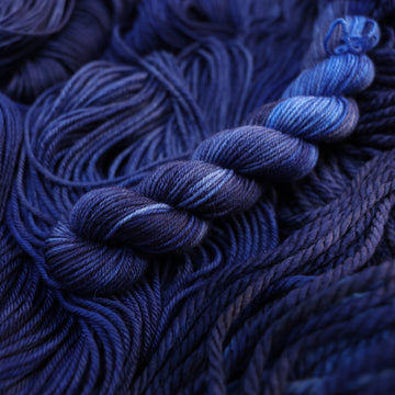A dark sapphire colored fingering-mini yarn on top of that same yarn, but its unwound.