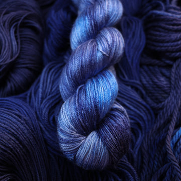 A dark shiny sapphire colored mulberry silk yarn on top of that same yarn, but its unwound.