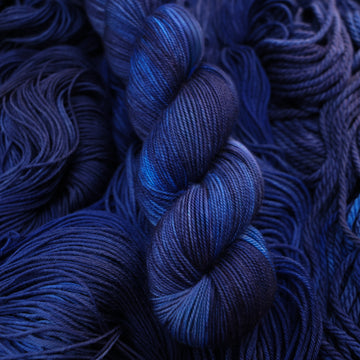 A dark sapphire colored sport yarn on top of that same yarn, but its unwound.
