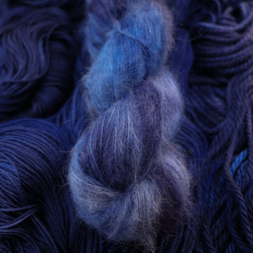 A dark sapphire colored suri alpaca yarn on top of that same yarn, but its unwound.