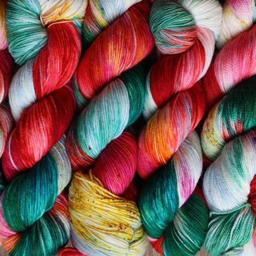 Red, green, light green, white, and yellow yarn stacked next to each other