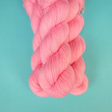 A light pink colored Fingering yarn on top of a light blue background.