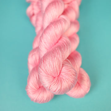 A light pink colored Silk yarn on top of a light blue background.